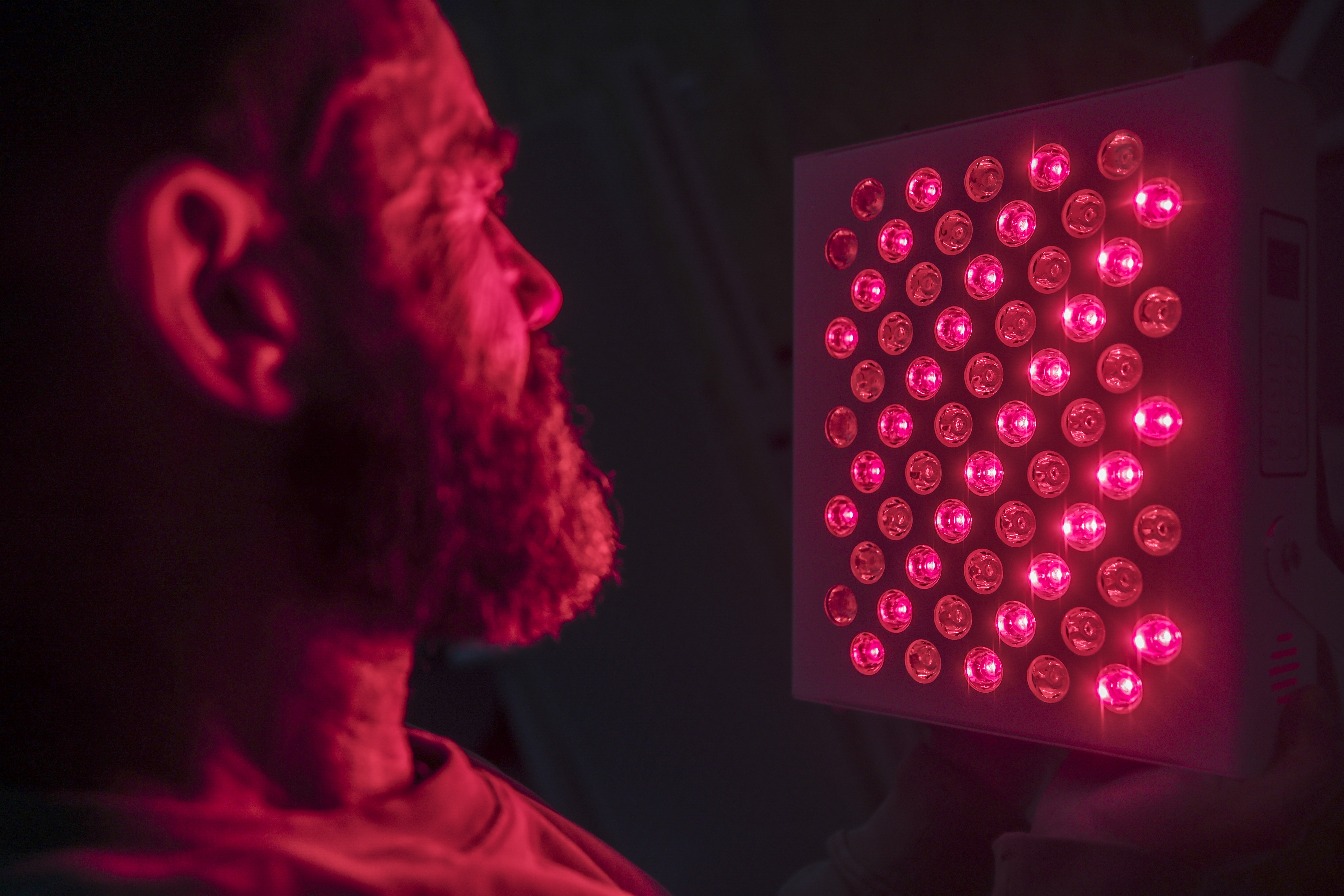 Mann lässt Gesicht von rotem Licht bestrahlen