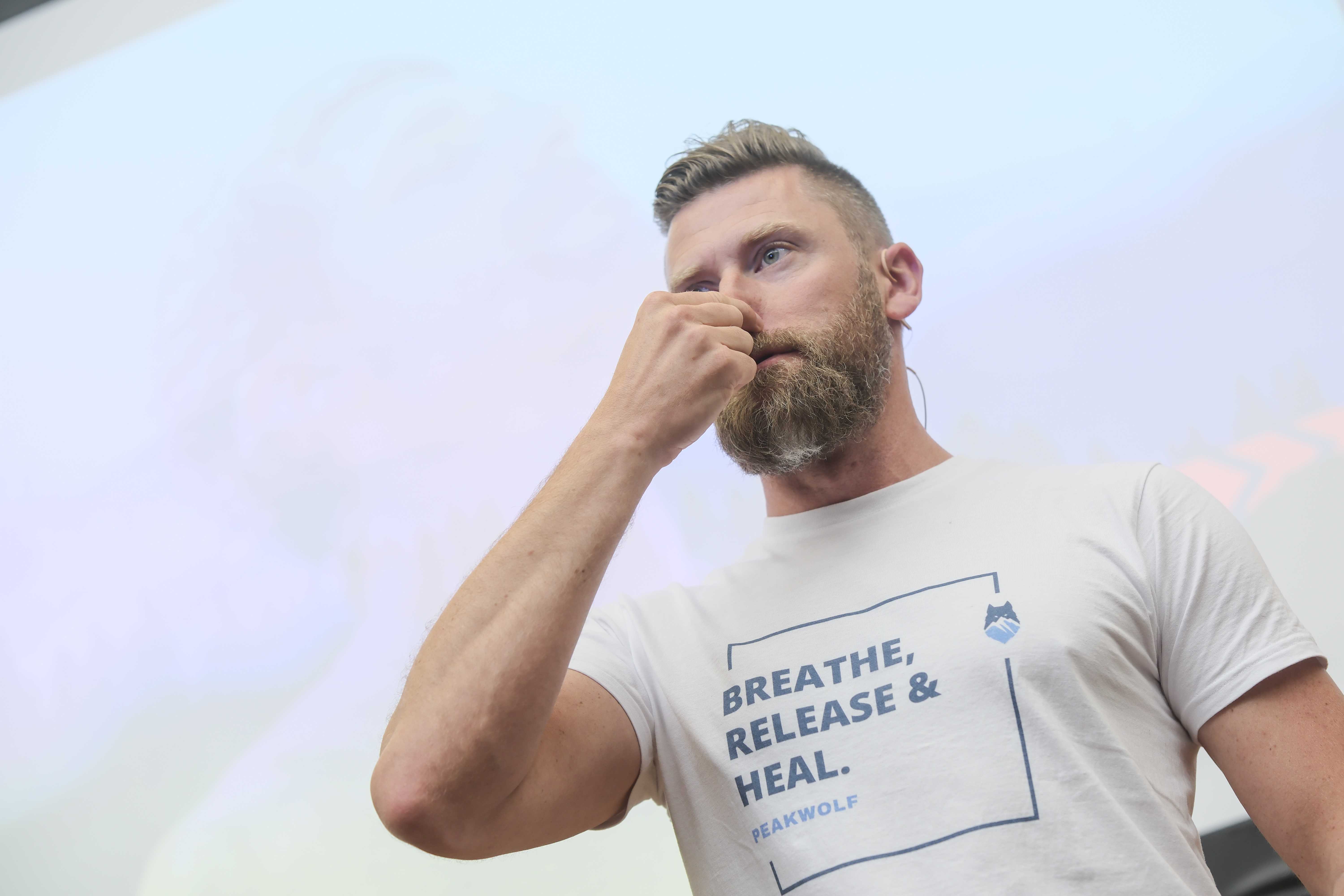 Mann zeigt Atemtechnik, auf seinem Shirt steht breathe, release & heal