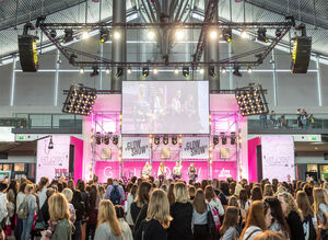 Menschenmenge blickt auf pinke Bühne mit vier Sprecherinnen zum Thema Glow Show