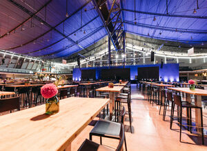 Leere Messehalle mit dekorierten Tischen und Bühne im Hintergrund