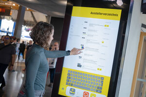 Frau bedient Touchbildschirm einer Stele