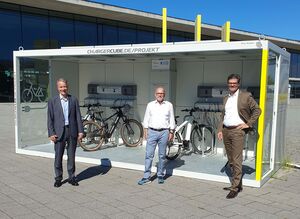 Die Geschäftsführer Roland Bleinroth (links) und Stefan Lohnert (rechts) mit dem Verkehrsminister Baden-Württembergs, Winfried Hermann, vor der Ladestation am Eingang West.