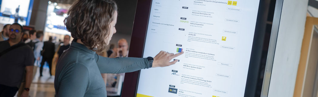 Digital Signage Frau bedient Touchbildschirm einer Stele