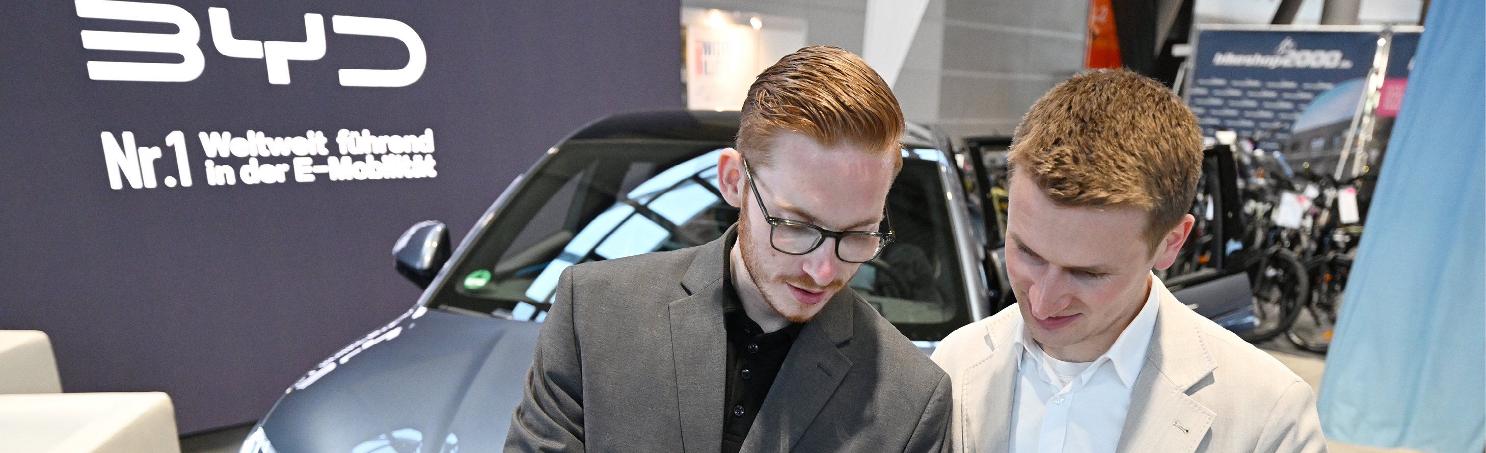 Zeigen Sie, wie Mobilität von morgen clever gestaltet werden kann! Zwei Männer beraten vor einem BYD Fahrzeug